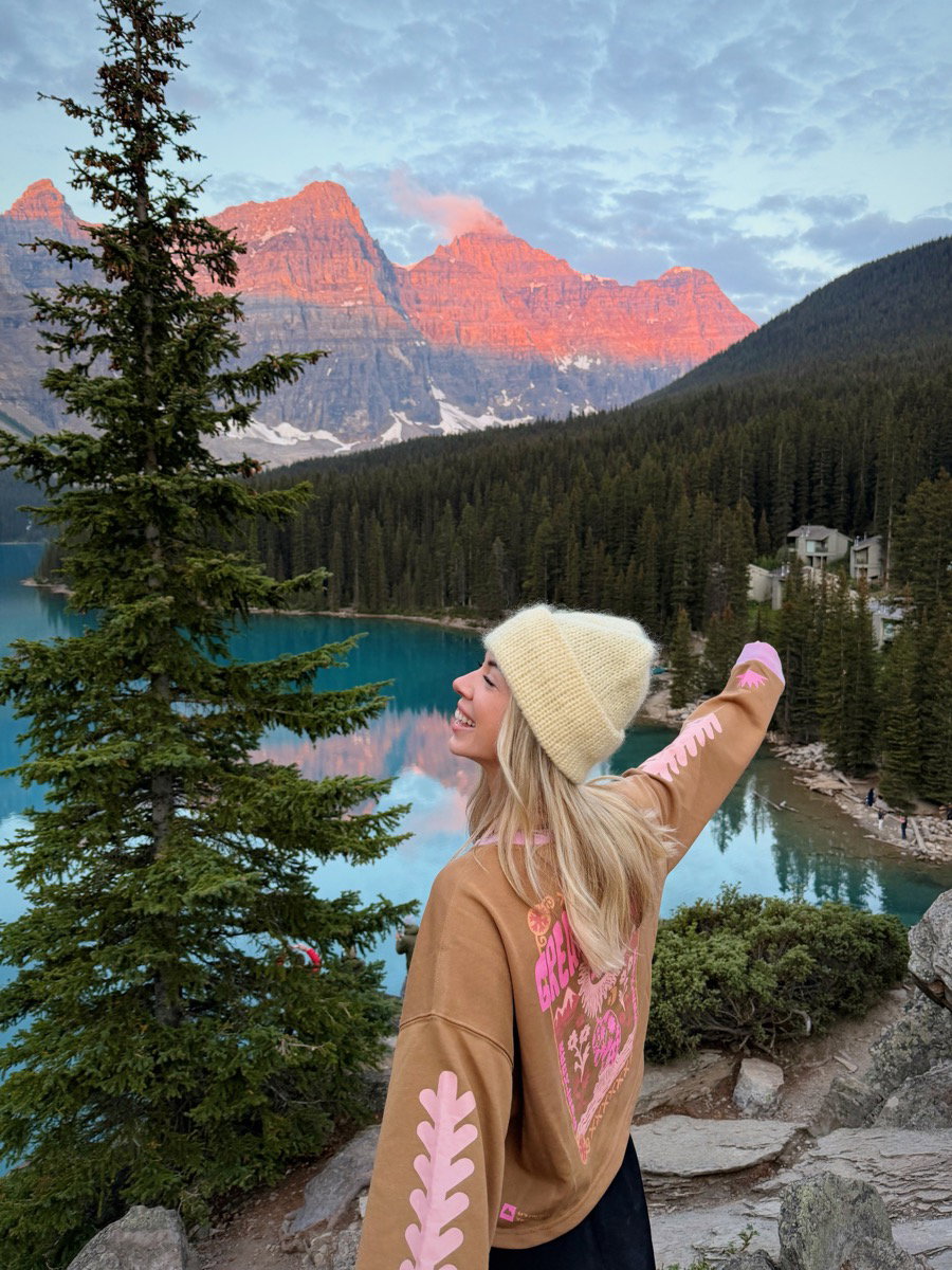Woman in a pink hoodie photographing the Valley of the Ten Peaks above Moraine Lake