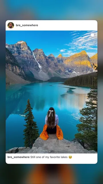 Woman sitting on a viewpoint above Moraine Lake and evergreen forest