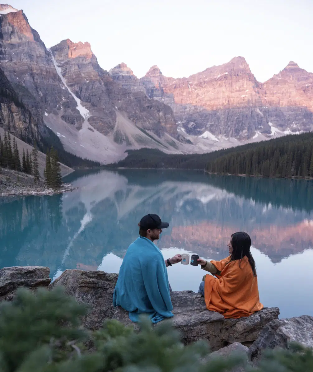 Romantic couple celebrating sunrise at Moraine Lake with coffee