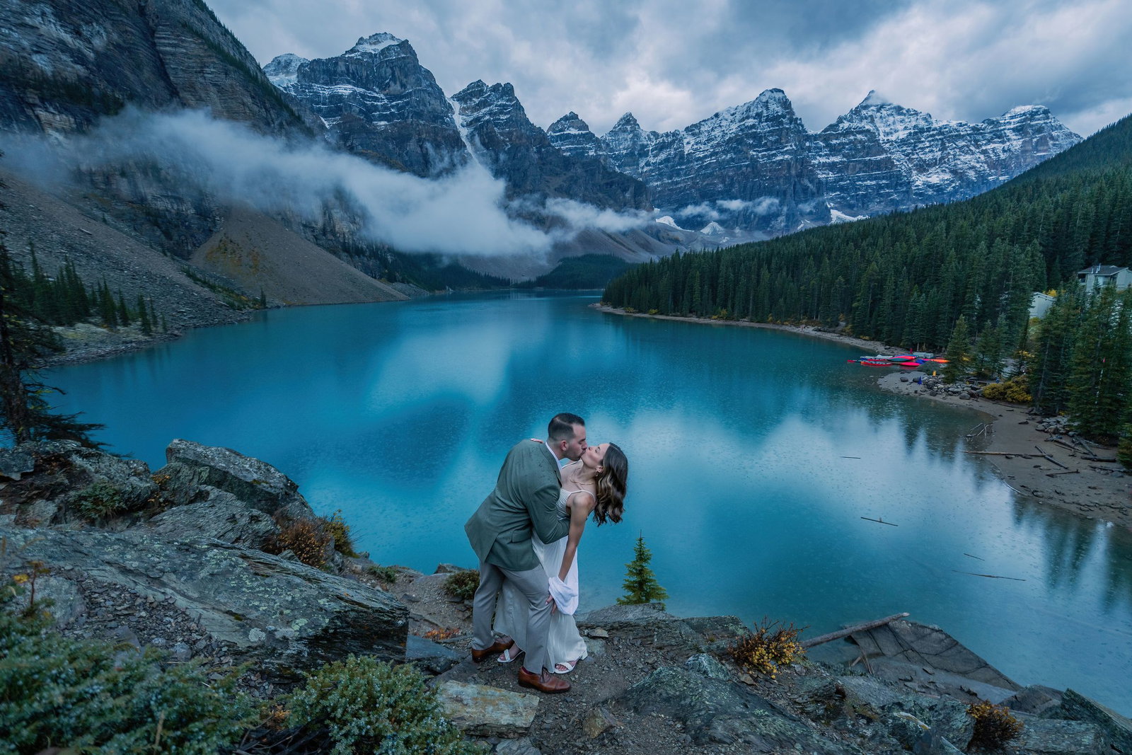 A couple enjoying the view of Moraine Lake in Banff National Park at sunrise.