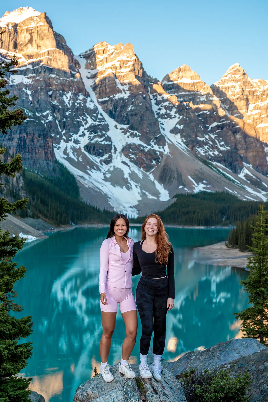 A group of girls enjoying the view of Moraine Lake in Banff National Park at sunrise.
