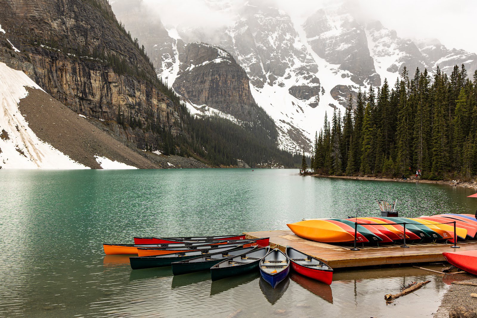 Colourful canoes at the Moraine Lake dock beneath snow-covered mountains